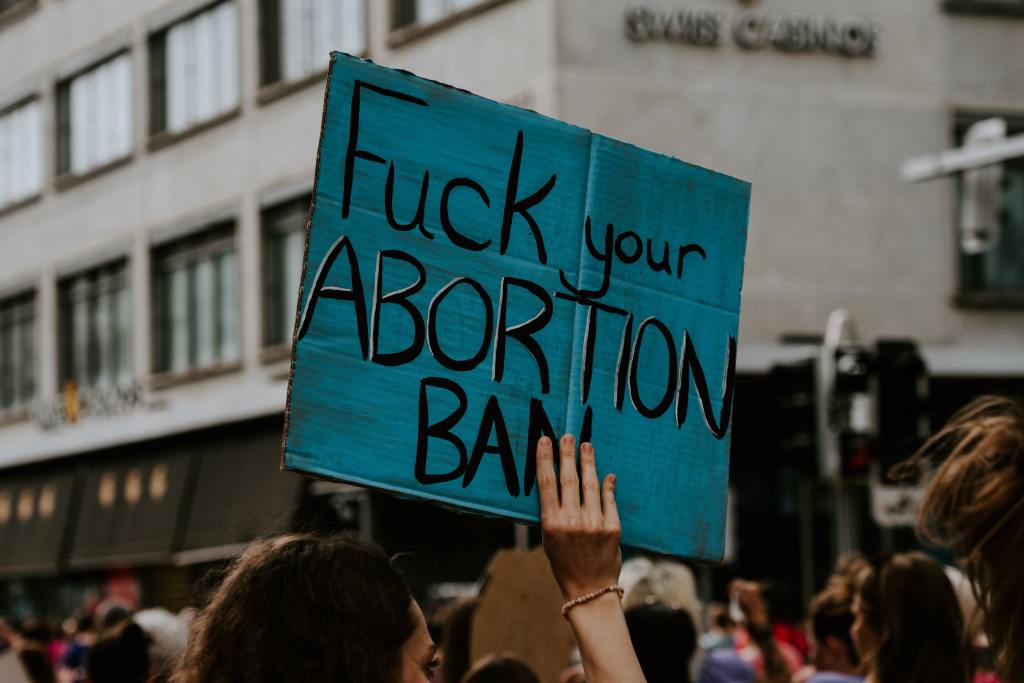 Image of a sign being held up that says "Fuck your Abortion Ban"